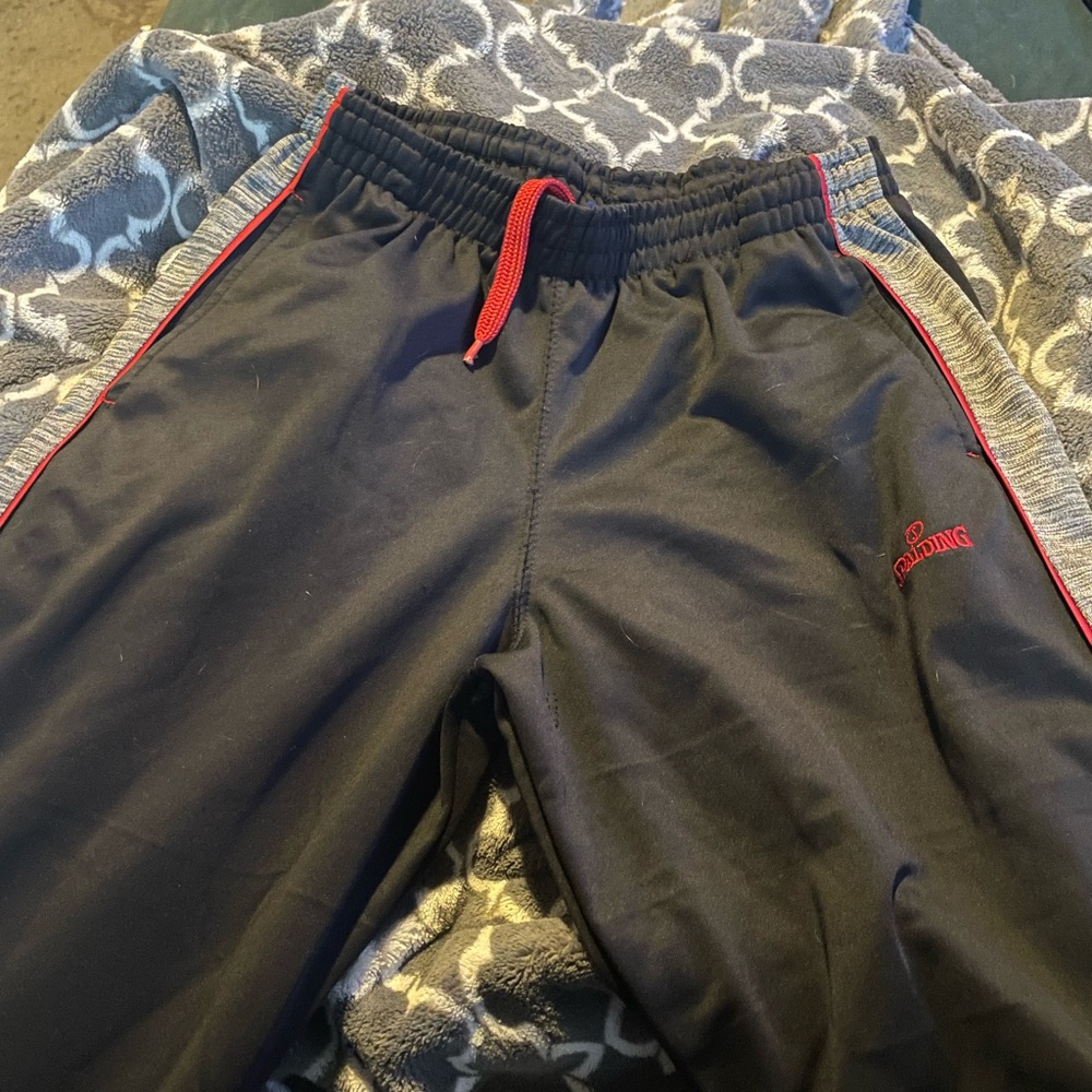 navy blue spalding track pants with gray stripes down side of legs